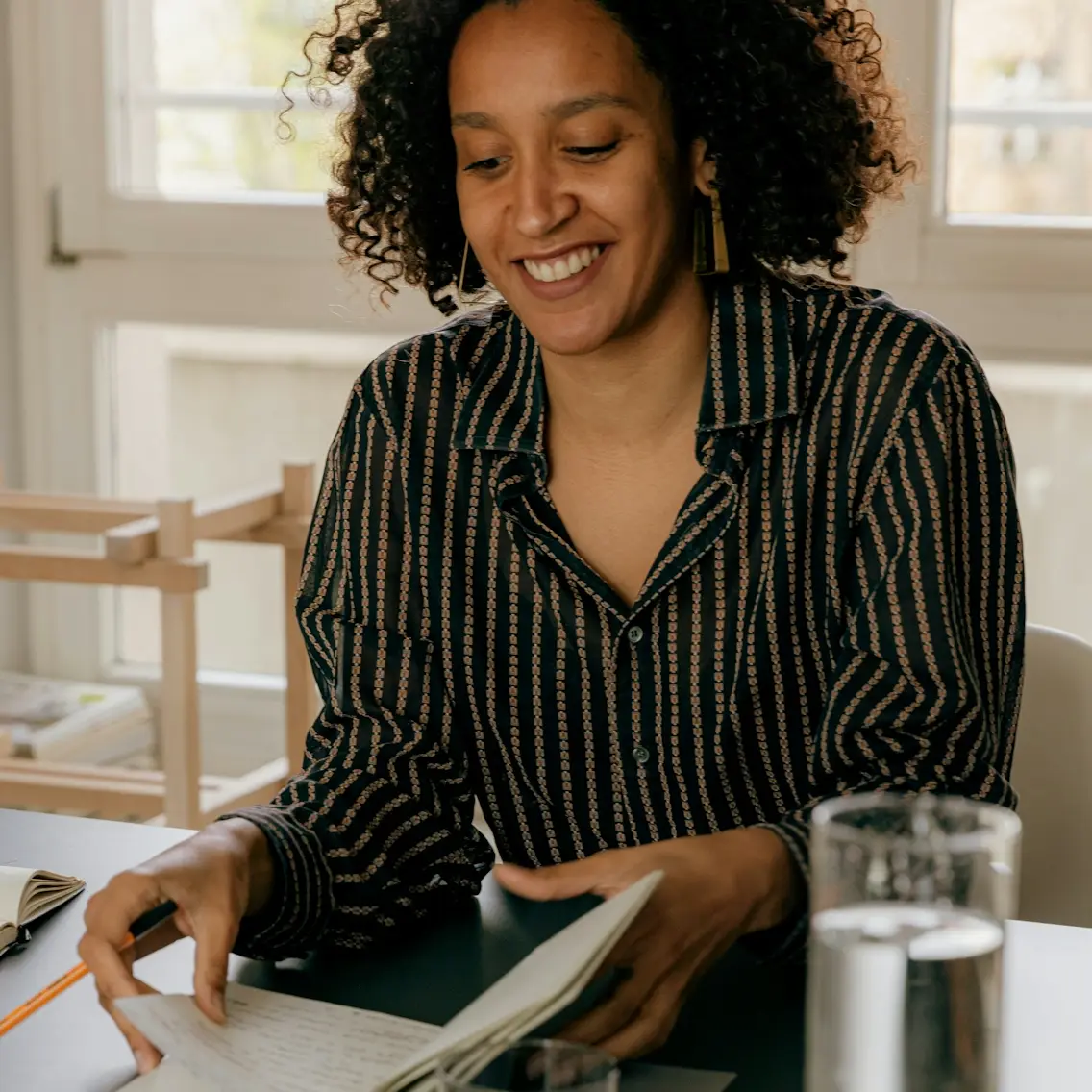 Woman seated at desk with notepad and glass of water